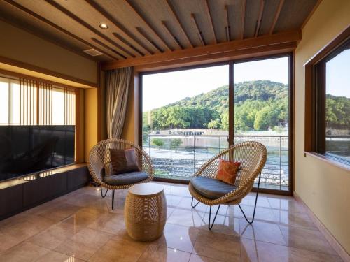 a room with two chairs and a large window at Hanayashiki Ukifune-en in Uji