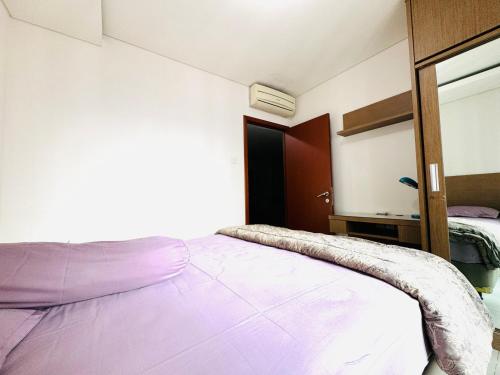 a bedroom with a large bed with purple sheets at Stunning High Floor Cozy Apartment Central Jakarta Near Grand Indonesia in Jakarta