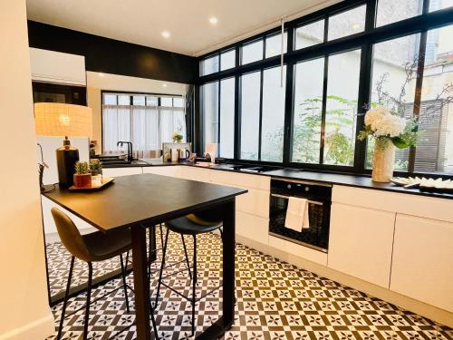 - une cuisine avec une table et quelques fenêtres dans l'établissement Appartements de charme du Général Leclerc - Place d'Erlon - Hypercentre - Gare - Reims, à Reims