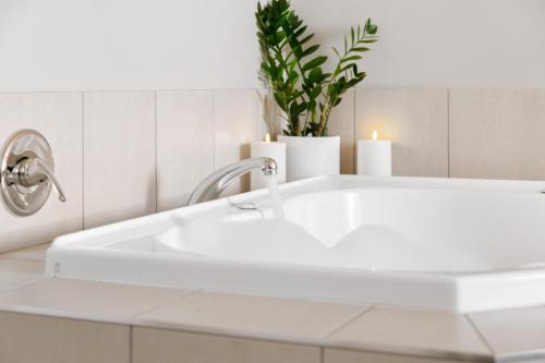 a white bathroom sink with two candles and a plant at Ocean Beach Wainui in Gisborne