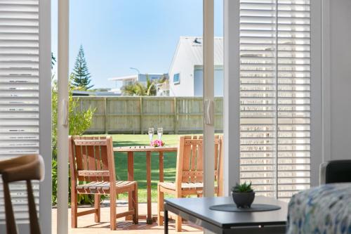 a patio with two chairs and a table on a porch at Ocean Beach Wainui in Gisborne