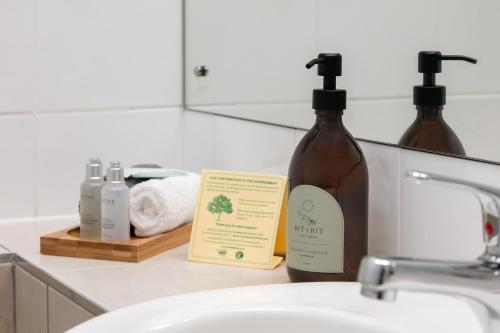 a bathroom sink with two bottles of soap and a mirror at Ocean Beach Wainui in Gisborne