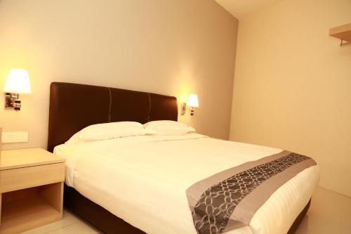 a bedroom with a large bed with white sheets at De Elements Business Hotel KL in Kuala Lumpur