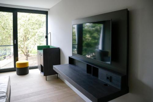 a living room with a flat screen tv on a wall at ATLANTIC Hotel Münster in Münster