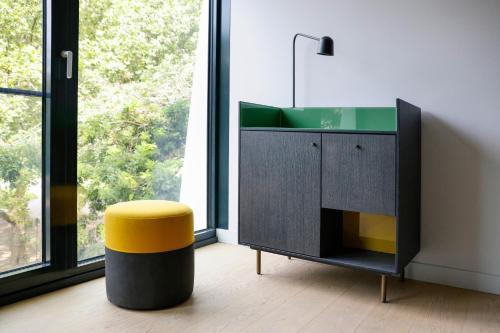a bathroom with a sink and a yellow stool at ATLANTIC Hotel Münster in Münster