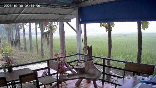 a dining room with a table and a view of a field at Banromsak resort - บ้านร่มสักรีสอร์ต in Ban Dok Kham Tai (1)