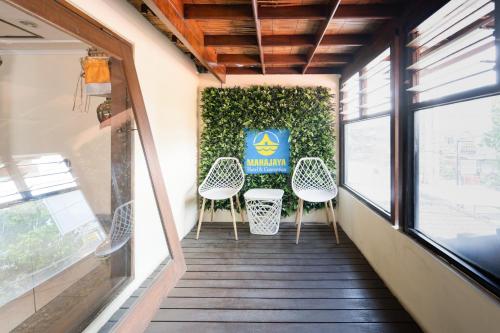 a corridor with chairs and a sign on a wall at RedDoorz Plus at Mahajaya Hotel Denpasar in Denpasar