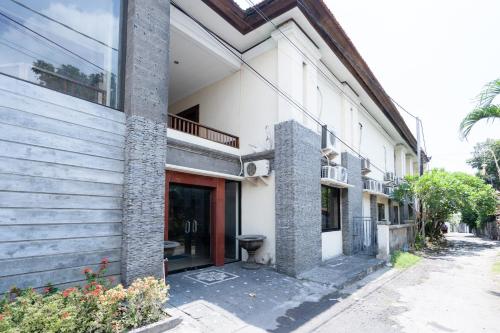 a white building with a red door on a street at RedDoorz Plus at Mahajaya Hotel Denpasar in Denpasar