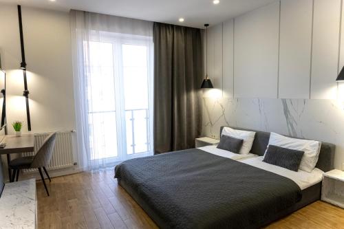 a bedroom with a bed and a desk and a window at Luxury Apartments “Bozdosh” in Uzhhorod