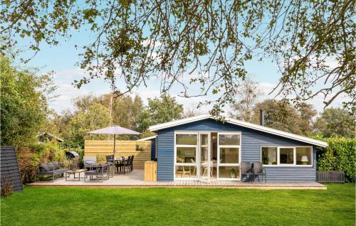 a blue tiny house with a deck and patio at Nice Home In Juelsminde With Kitchen in Juelsminde