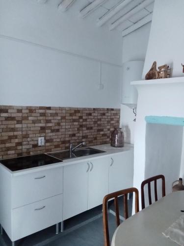 a white kitchen with a sink and a table at Casa dos Josés in Elvas