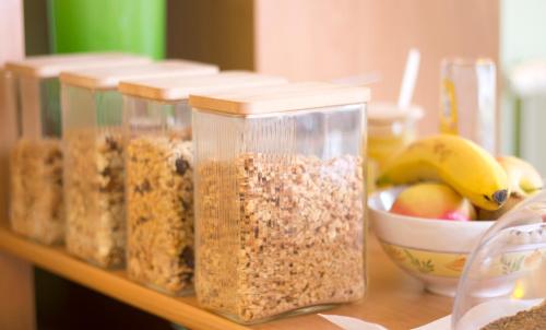 a shelf with four containers of granola and a bowl of fruit at Hus op de Diek in Sankt Peter-Ording