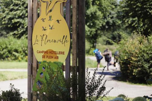 a sign for a park with people biking down a trail at Camping Le Florenville in Florenville