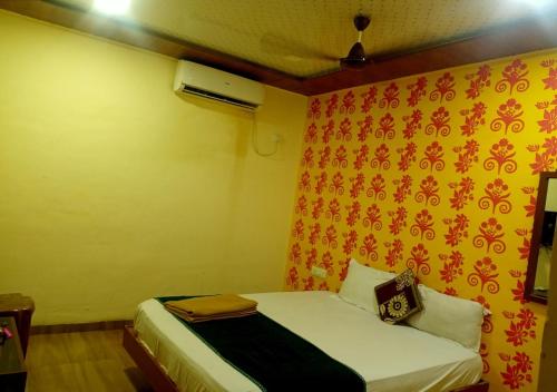a small bedroom with a bed with a red and yellow wall at Hotel Geetanjali St Bus Stand Panvel in Panvel