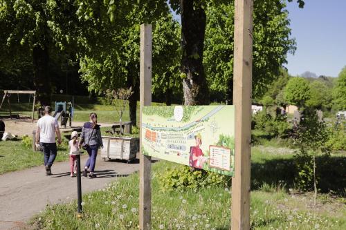 a sign in a park with a family walking at Camping Le Florenville in Florenville