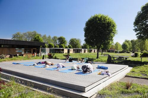 a group of people doing yoga on a wooden deck at Camping Le Florenville in Florenville