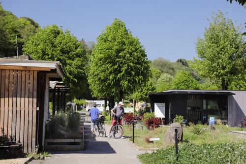 two people riding bikes down a sidewalk next to a building at Camping Le Florenville in Florenville