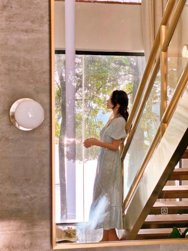 a woman in a dress looking out of a window at iTree Guanhu Academy Huizhou West Lake in Huizhou