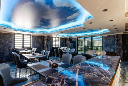 a restaurant with tables and chairs and a ceiling with a mural at РИМ Grand Hotel in Almaty