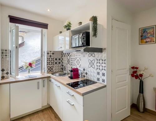 une cuisine avec des armoires blanches et une fenêtre dans l'établissement Canopee rue Carnot Annecy, à Annecy