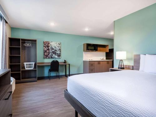 a bedroom with a bed and a desk and a kitchen at ECHO Suites Extended Stay by Wyndham Indianapolis AmeriPlex in Indianapolis