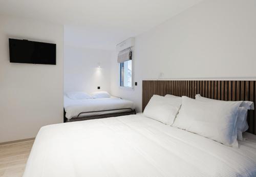 a bedroom with a large white bed and a tv at Appart Hotel Neostelia in Annecy