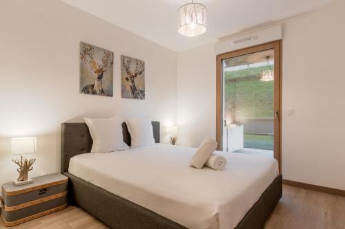 une chambre avec un grand lit blanc et une fenêtre dans l'établissement Le 002 - Proche Telecabine - Terrasse, à Saint-Gervais-les-Bains