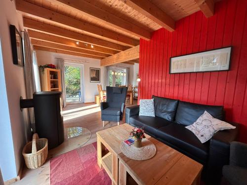 a living room with a black couch and a red wall at Haus Anemone in Wieck
