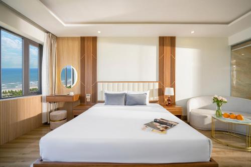 Un dormitorio con una gran cama blanca y un sofá. en 7 Seven Sea Hotel, en Da Nang