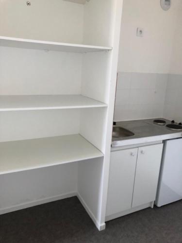 a white kitchen with white shelves and a counter at Aladin resort in Bouconvillers