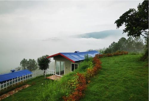 a small house with a blue roof on a hill at Adaara Retreat - Pet Friendly Cottages, Almora in Almora