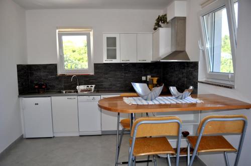 une cuisine avec des placards blancs et une table en bois dans l'établissement Apartments Sandro, à Sali
