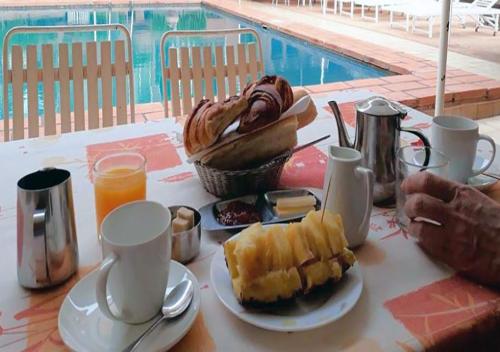 a table with a breakfast of coffee and a basket of food at Hôtel L'Auberge in Bobo-Dioulasso