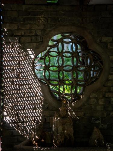 a brick wall with a stained glass window at PuYuan Laoyangfang Huayuan GuestHouse in Xi'an