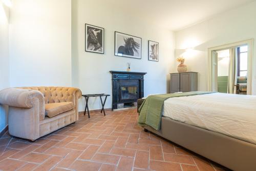 a bedroom with a bed and a chair and a fireplace at Origine Country Farm in Tabiano