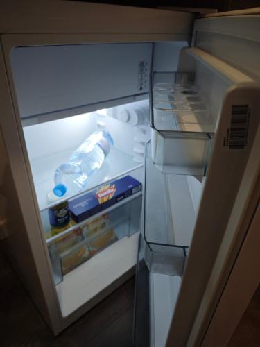 an open refrigerator with a bottle of water and food at Dunja Apartmans in Belgrade