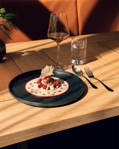 a plate of food on a table with a glass of wine at ATLANTIC Hotel Münster in Münster