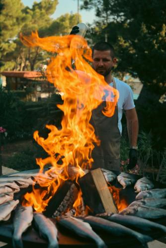 a man is standing next to a fire at Family Resort Urania in Baška Voda