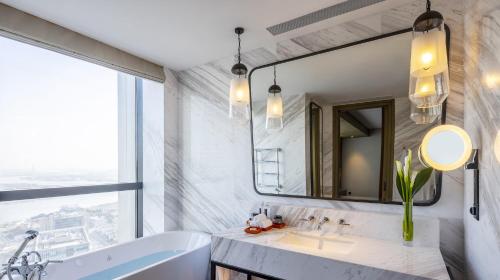 a bathroom with a tub and a sink and a mirror at MGM Shanghai West Bund in Shanghai