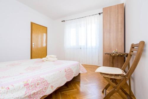 ein Schlafzimmer mit einem Bett und einem Holzstuhl in der Unterkunft Apartment Andjelko G in Šilo