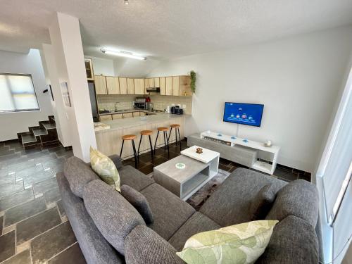 a living room with a couch and a kitchen at Salty Sunset Self Catering in Langstrand