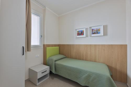 a bedroom with a green bed and a window at Camping Village Le Calanchiole in Capoliveri