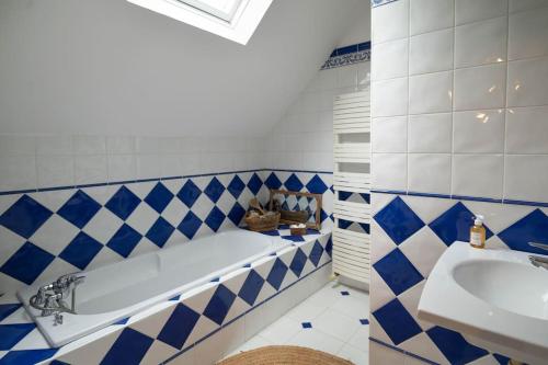La salle de bains bleue et blanche est pourvue d'une baignoire et d'un lavabo. dans l'établissement Longère de Charme, bord de Loire, à Gennes