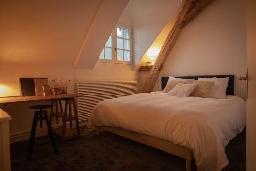 une chambre avec un lit, un bureau et une fenêtre dans l'établissement Longère de Charme, bord de Loire, à Gennes