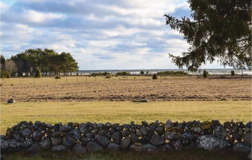 a stone fence in front of a field with trees at Two-Bedroom Holiday Home In Lottorp in Löttorp