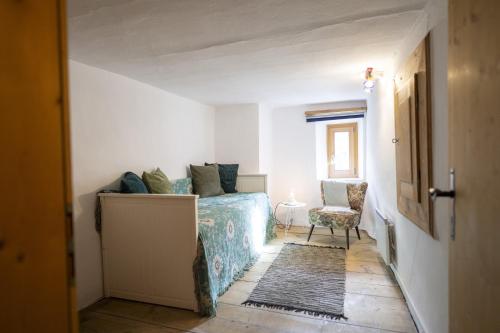 a bedroom with a bed and a chair and a window at Chasa San Geer Sains in Scuol