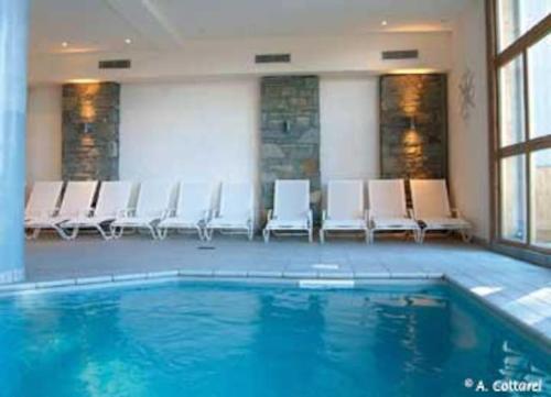 une chambre avec une piscine dotée de chaises blanches et une chambre avec dans l'établissement Duplex famille 10 à 12 personnes station les coches La plagne, à La Plagne Tarentaise