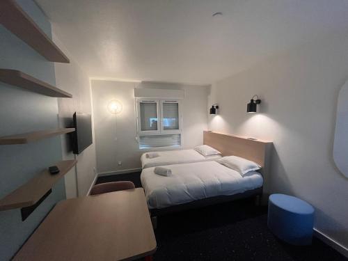 a hotel room with two beds and a table at Appart'Hôtel Lauréades Clermont-Ferrand Centre Jaude in Clermont-Ferrand
