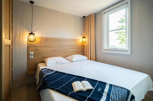 派拉克Camping Le Sequoia的一间卧室配有一张床,上面有两本书