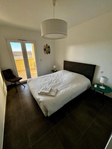 - une chambre avec un lit blanc et 2 tables dans l'établissement Appartement Rossignol, à Saint-Florent